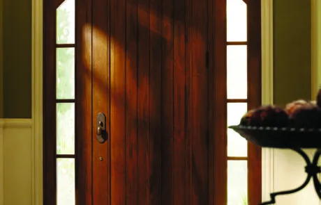 Arched wood entry door with glass panels viewed from a foyer
