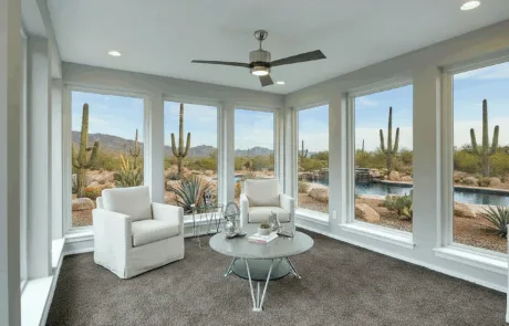 Sunroom with white windows overlooking a desert backyard and pool