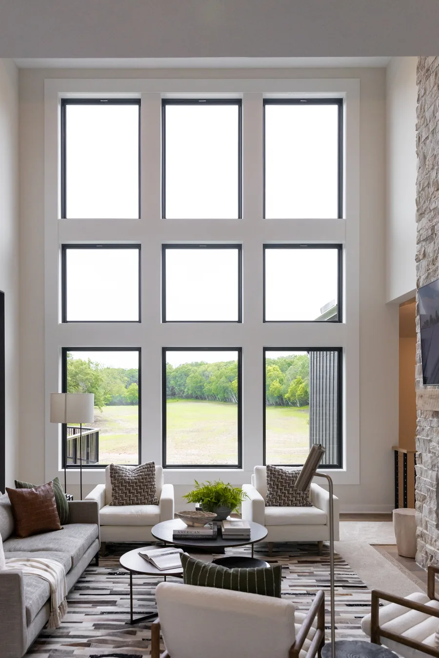 Two-story living room with a stacked wall of black-framed picture windows
