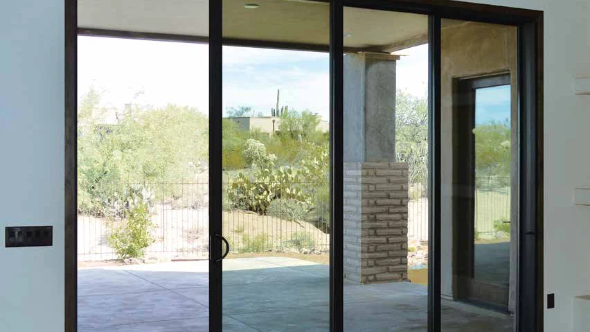 IWC Ambassador aluminum multi-slide door with dark frames, closed, looking onto a desert patio