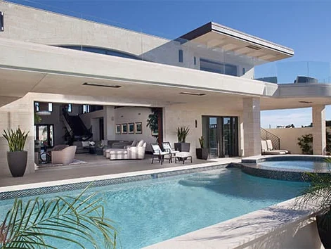 Sliding glass doors pocketed into the wall of a white stucco home beside a pool, leaving the opening clear