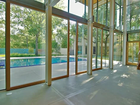 Multi-panel sliding glass wall in a straight run along a living room, standing closed with a pool beyond