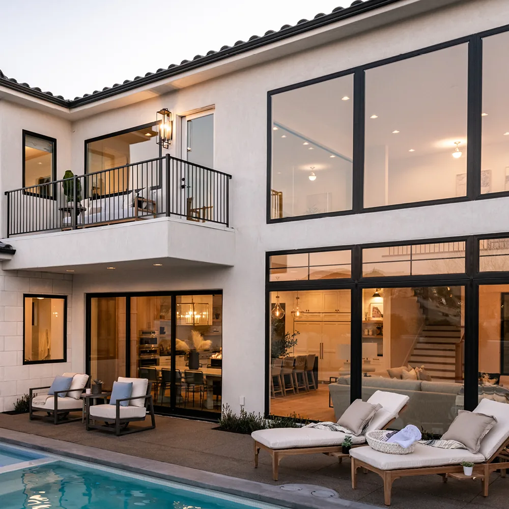 Black framed sliding glass doors, closed, on a two storey home above a pool deck