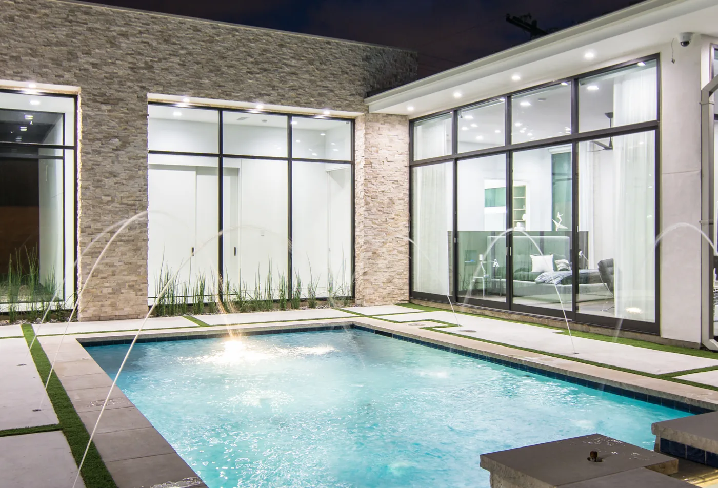 Glass doors on two sides of a courtyard pool, meeting at a stone corner pier