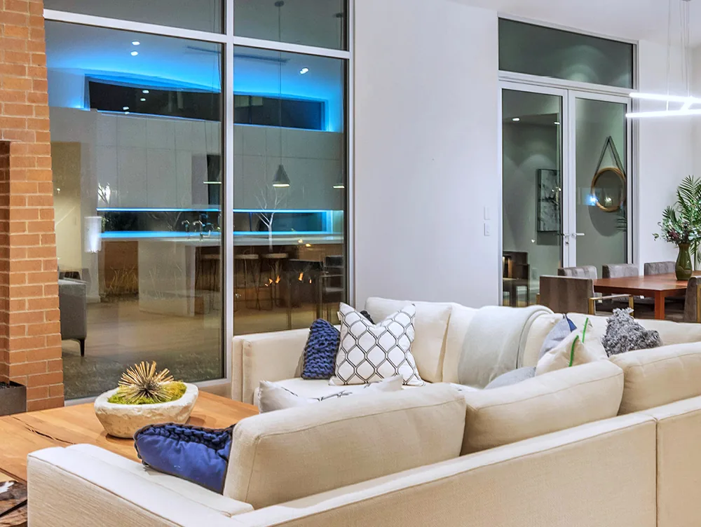 Interior view of a sliding glass wall in the evening with a lit kitchen beyond