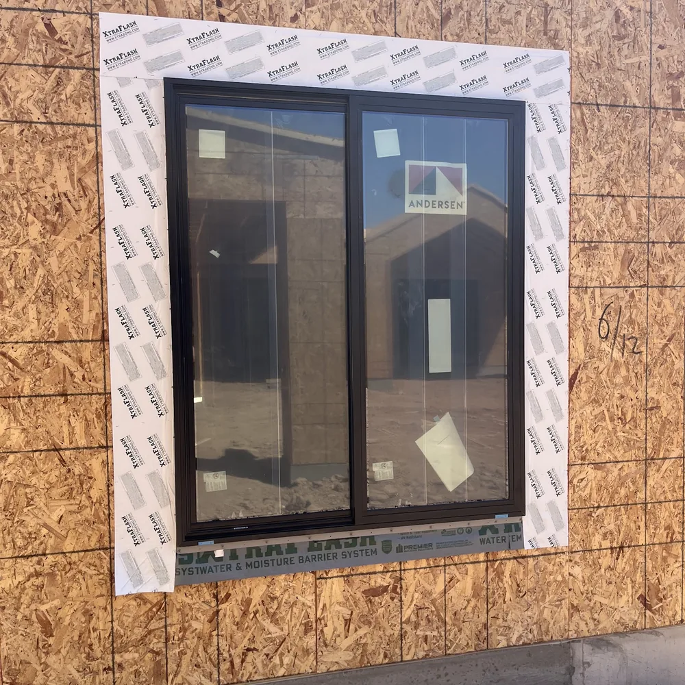 New construction window set into a framed opening in OSB sheathing with the nailing fin taped into the weather barrier on a Phoenix build