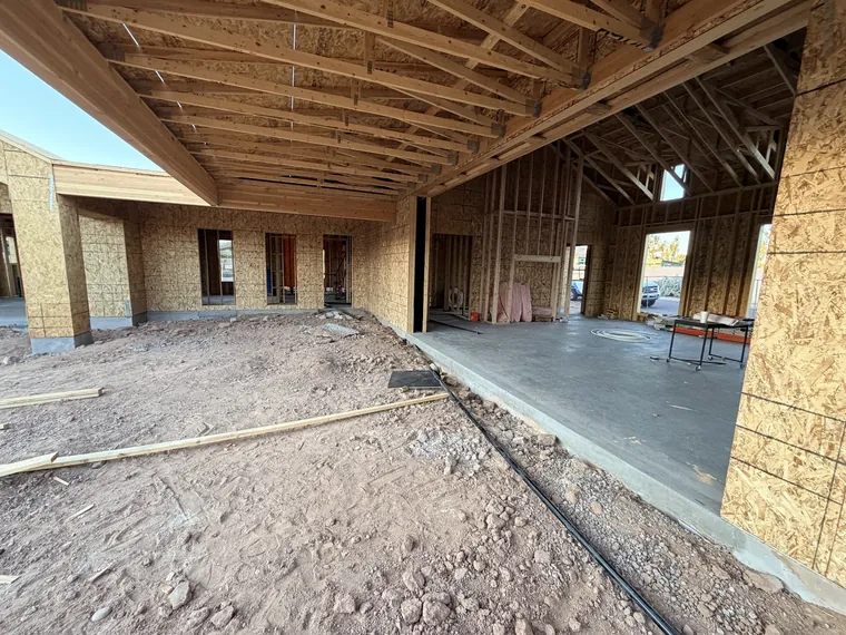 Great room of a Phoenix new build at framing stage with exposed roof trusses and the window and door openings framed