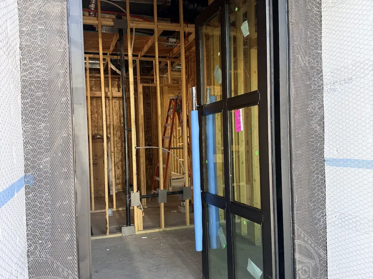 Black framed glass door set into a framed opening inside a Phoenix home under construction