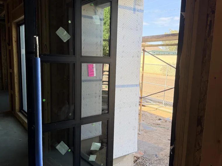 Black framed glass entry door set into a framed opening with house wrap on a Phoenix new build