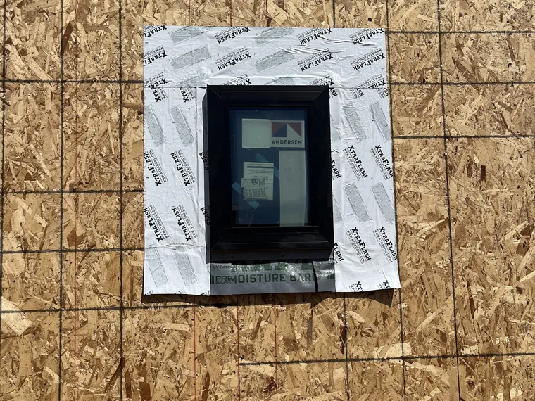 Small black framed new construction window with the nailing fin taped into the weather barrier on a Phoenix build