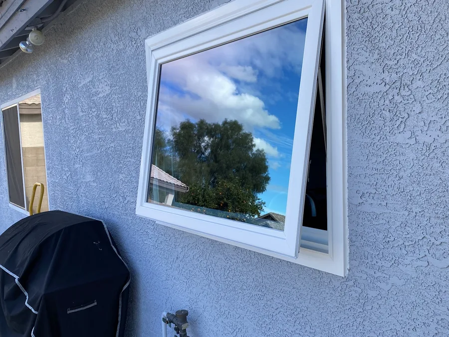 White-framed awning window cranked open on a stucco wall, a Noble project