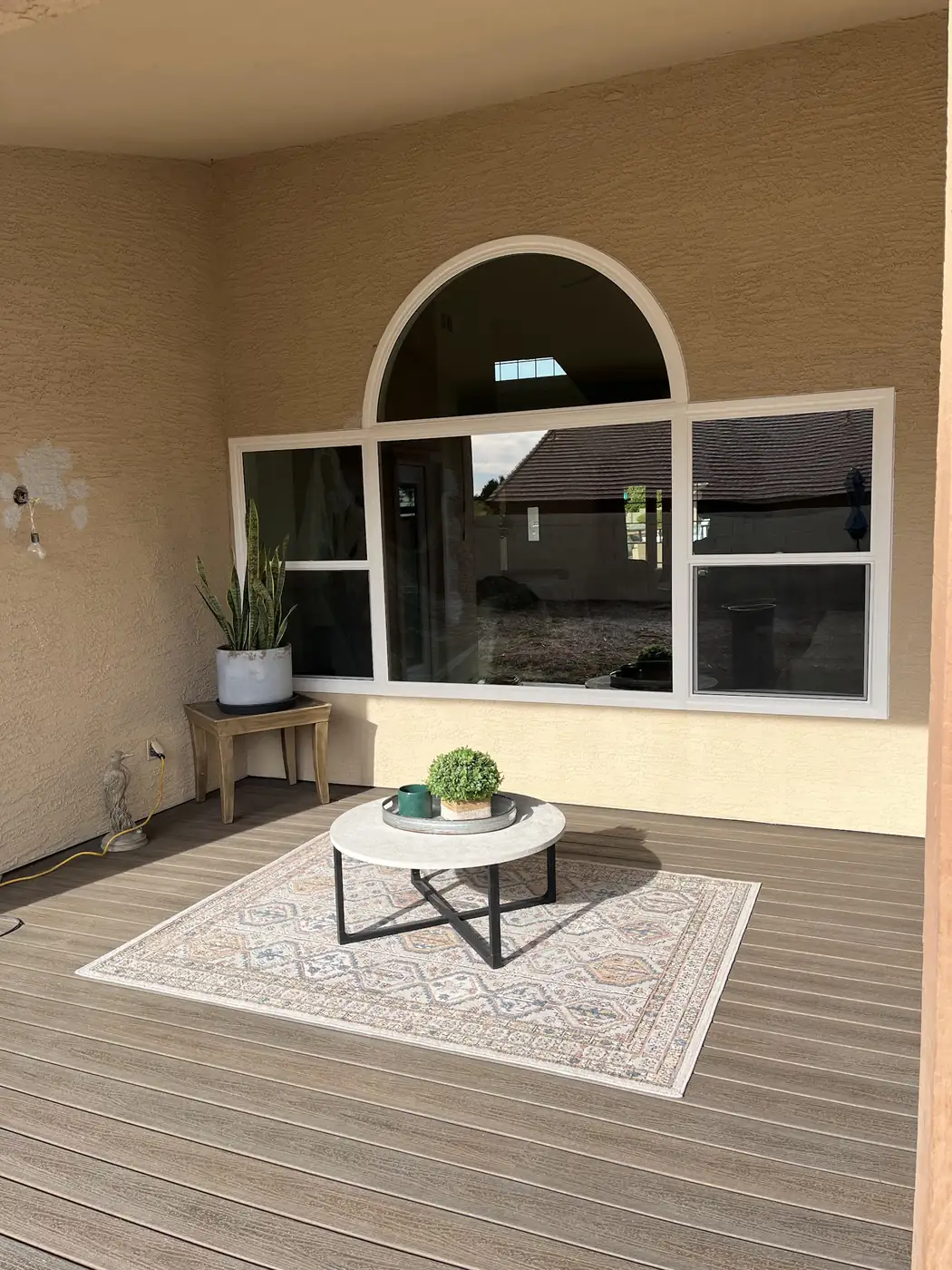 Arched window over a three-panel window on a covered back patio, after replacement