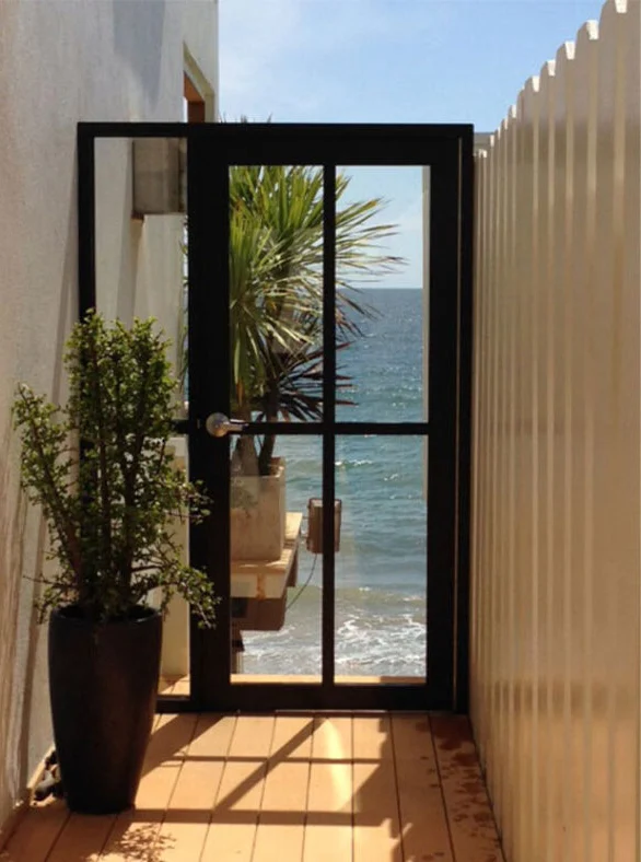 Single PRL Glass Systems aluminum door with a black frame and divided glass, opening onto an ocean view
