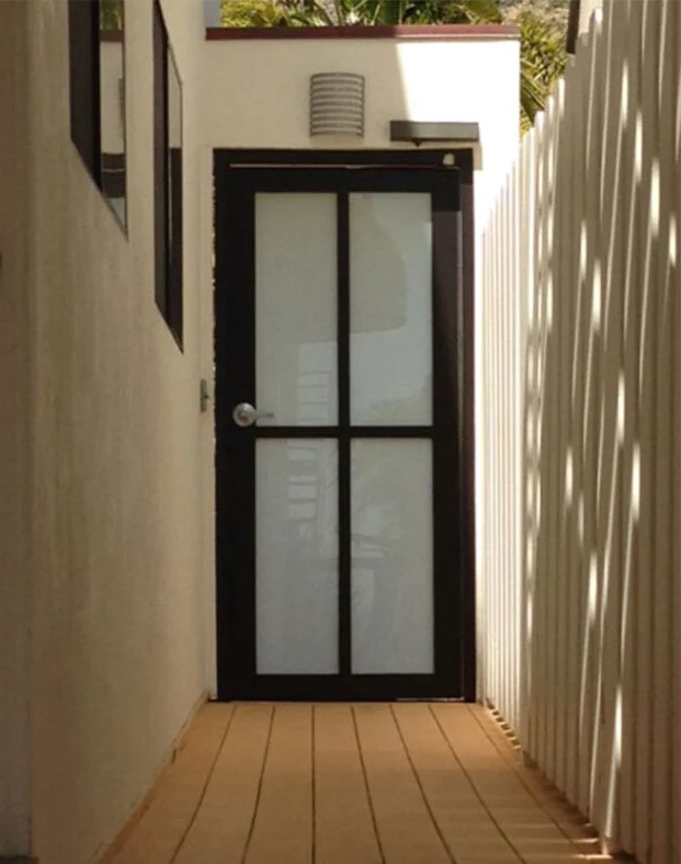 Single PRL dark aluminum door with frosted divided glass at the end of a side yard