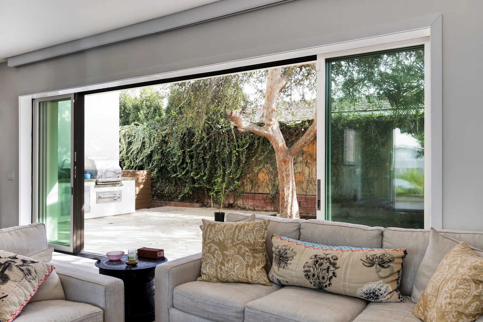 Pocketing sliding glass door open from a living room onto a patio, with the panels slid into the wall at the left