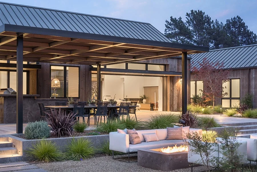 Stacking door open at dusk from a great room onto a covered patio, with the panels parked at the right jamb